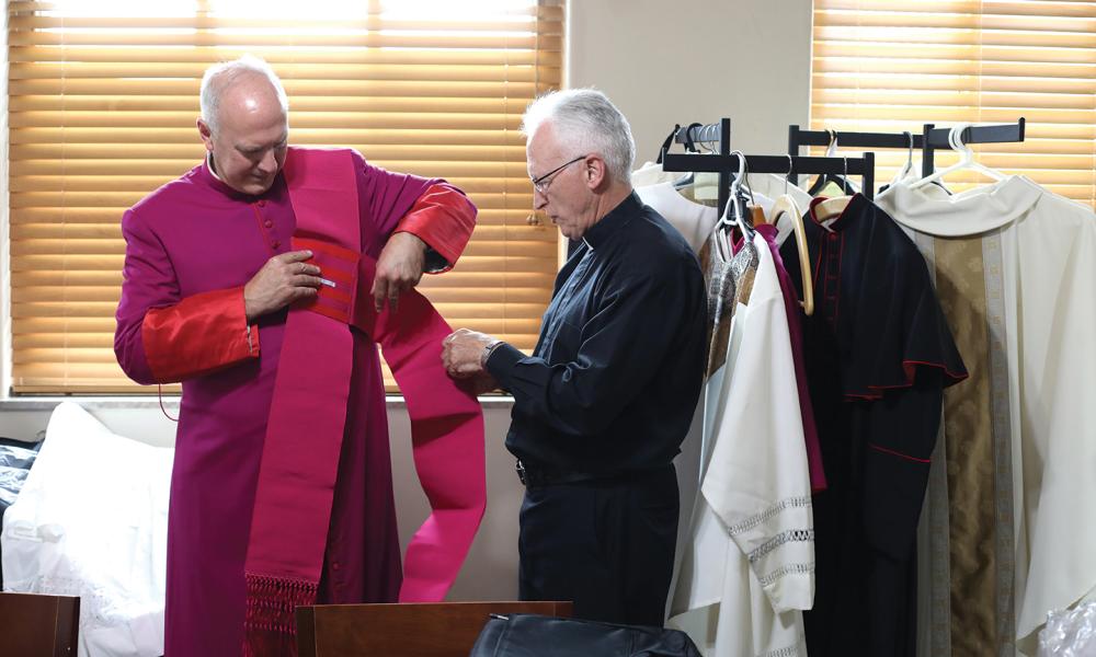 Bishop Boyea helps Bishop-elect Vincke with his vestments.