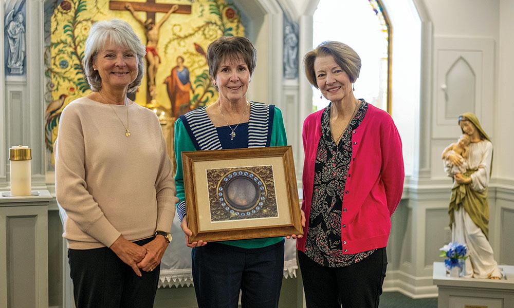 Kathy Tarnacki, Beth Thorrez, and Kathy Kryst hold an image of Jackson's own eucharistic miracle