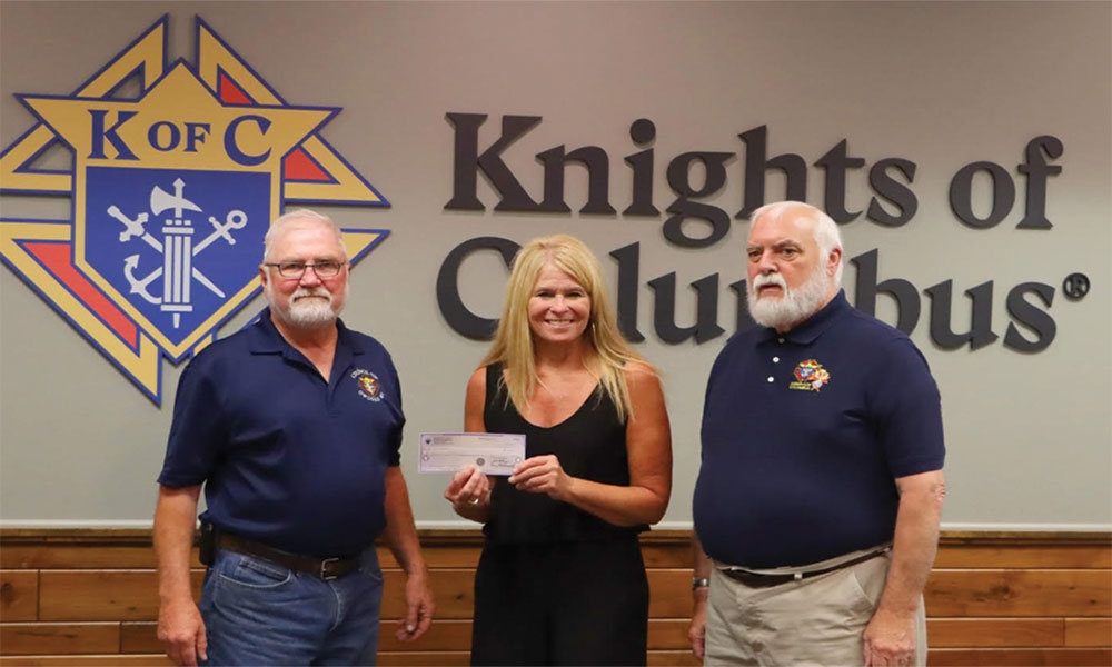 Grand Knight and Tootsie Roll Drive chair Gary Bendall (left), Grand Knight Dan Koch (right), Mid-Michigan Executive Director Lynn Kovalik (center)