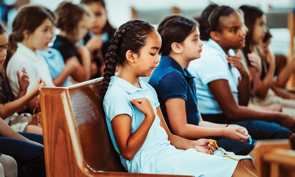 Children praying the rosary in pews