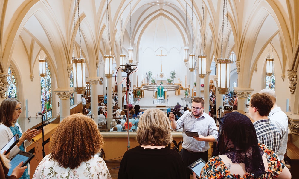 People singing in a church choir loft overlooking Mass