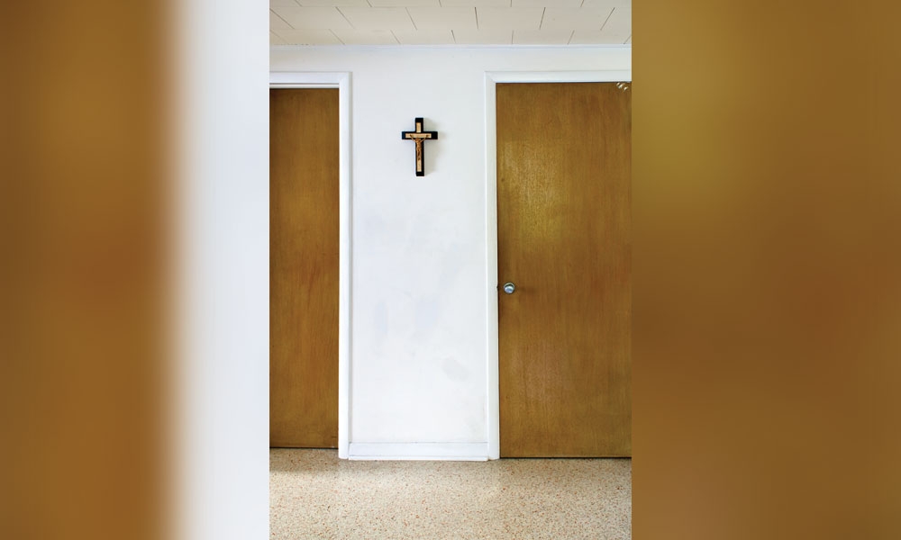 A crucifix nailed to a white wall between two doors