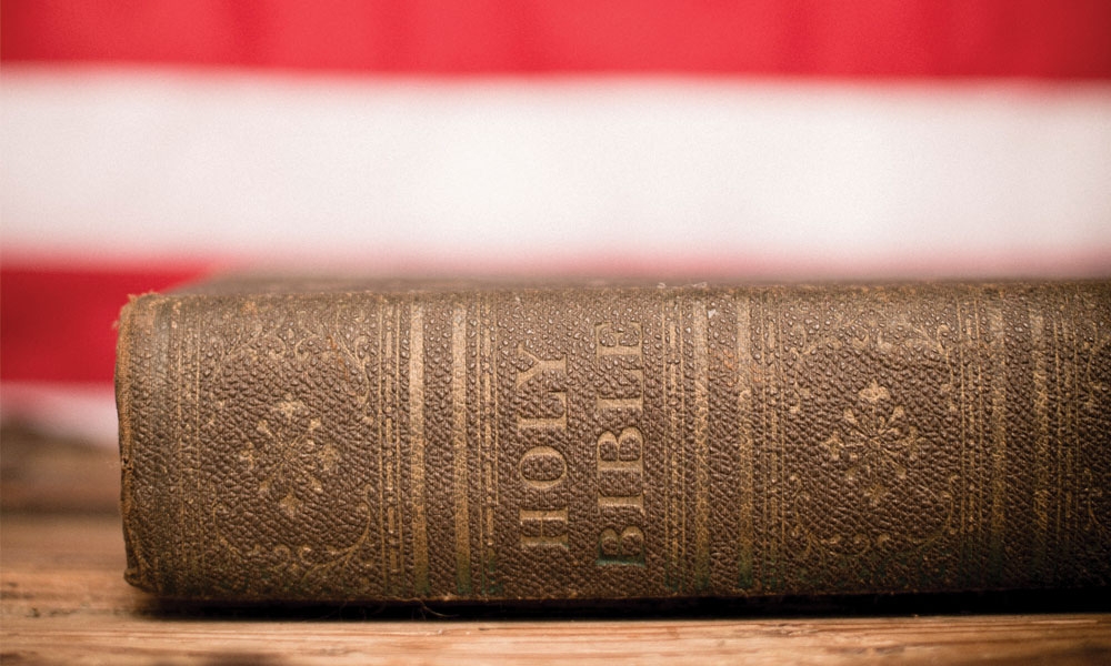 A Bible in front of an American flag backdrop