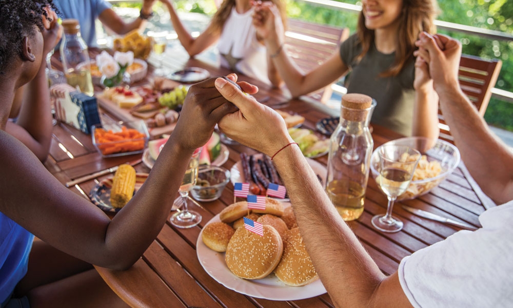 Group of people praying over an outdoor meal