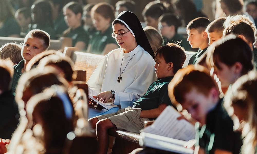 Sister reading to a Catholic student in a pew