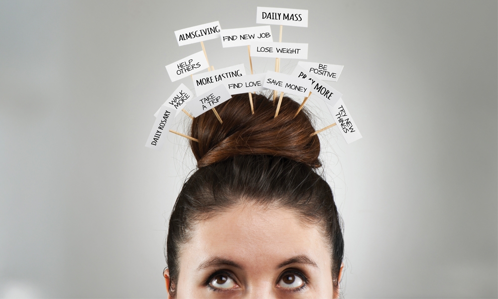 Image of a woman with hair in a bun on top of her head and small picket signs with various words sticking out from the bun