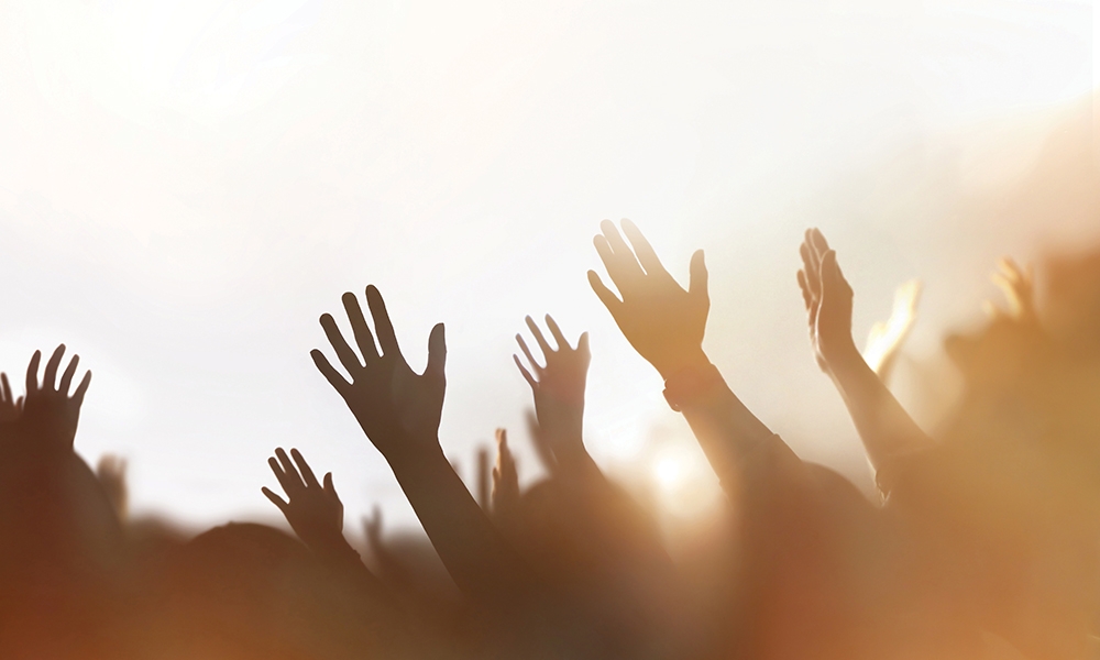Image of silhouettes of hands raised in the air in praise and worship