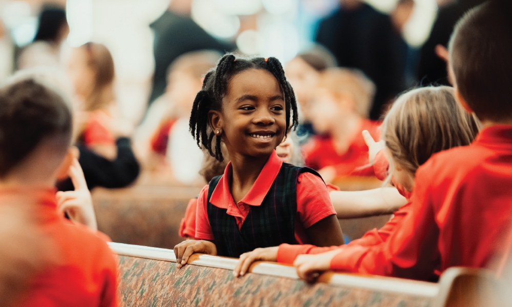 Smiling young girl with classmates in pews